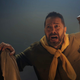 Two men in period adventurer's garb pierce the foggy darkness, one holding a lantern aloft and looking frightened.